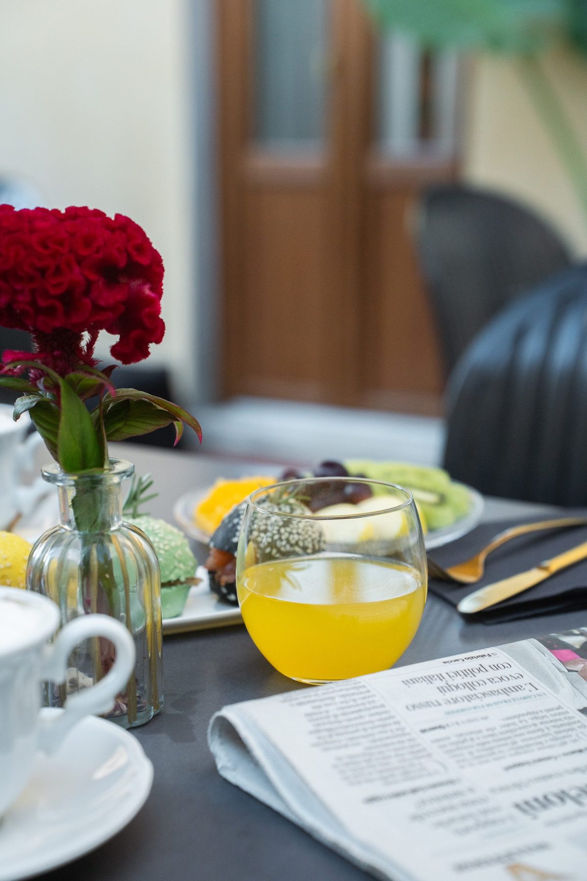 Tavolo della colazione con fiori, spremute e cappuccino