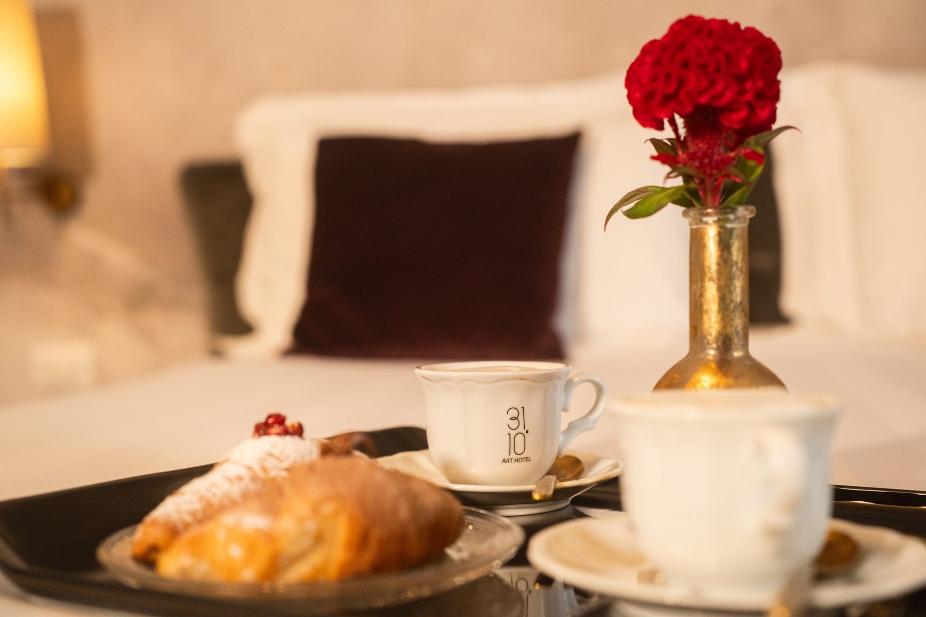 Vassoio della colazione in camera con croissant e rosa